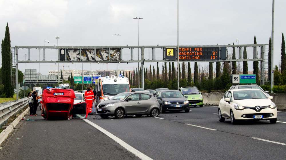 Wypadek komunikacyjny na autostradzie. Czerwony samochód leży na dachu.